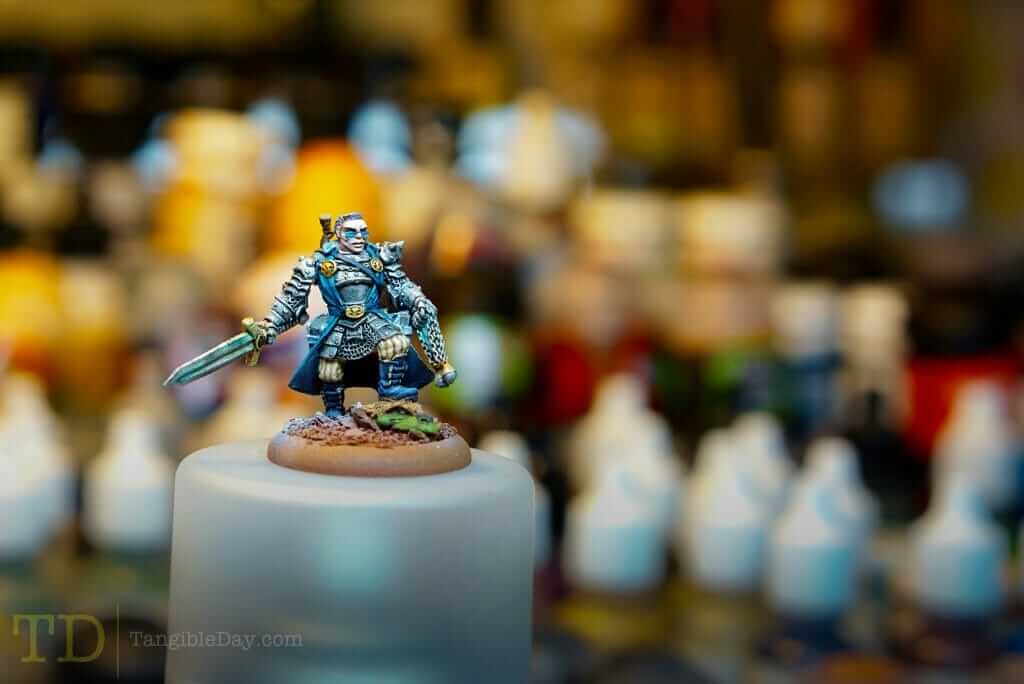 Miniature figure painted under proper lighting with bottles of paint blurred in the background.