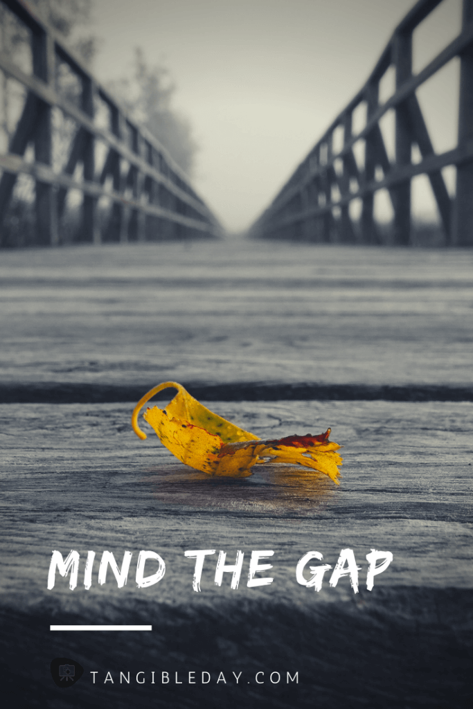 A single yellow leaf on a wooden bridge with text overlay "Mind the Gap" and foggy background


