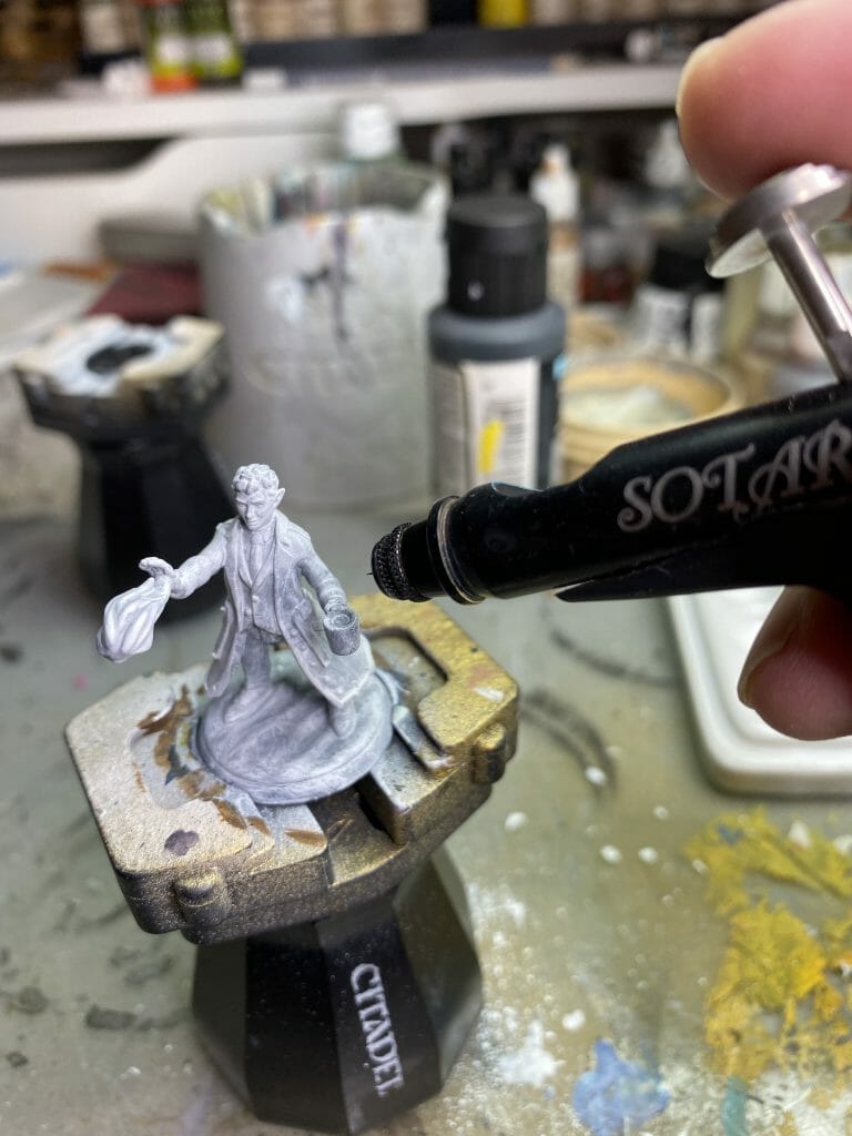 Airbrushing primer onto a miniature mounted on a painting handle