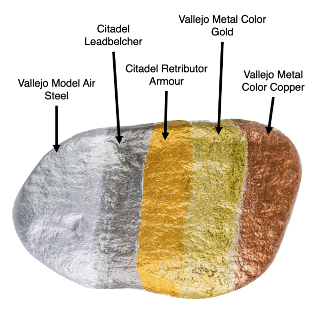 Five different metallic paints applied to a rock with labeled tone comparison