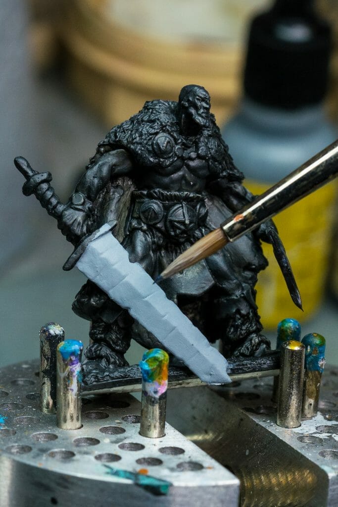 base coating a sword on a model RPG barbarian primed black