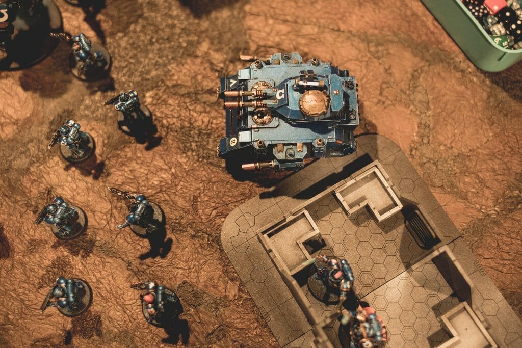 AI Enhanced Wargaming and Tabletop RPGs (Tips and Uses) - A bird's eye view of a collection of Space Marines from Warhammer 40k on a brown battle map tabletop