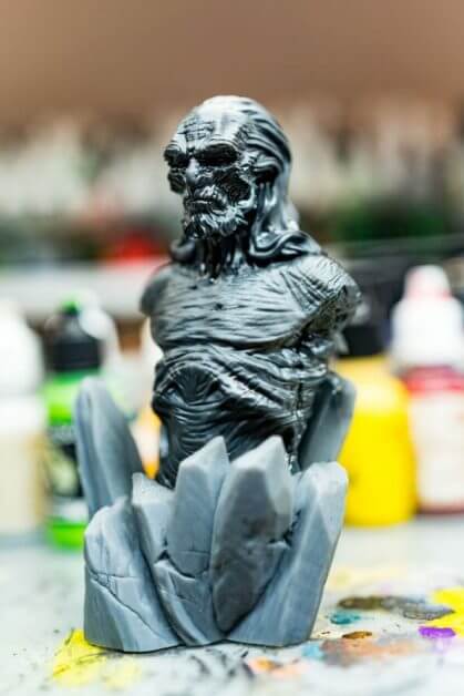 Angled photo of primed miniature with Vallejo Surface Primer, gray dark color