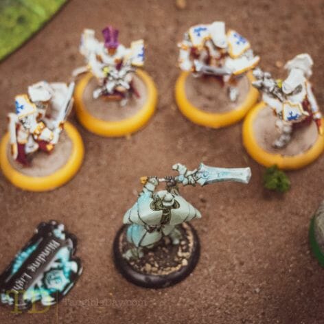 Miniature game of warmachine with a menoth group of models surrounding a Retribution of Syrah model