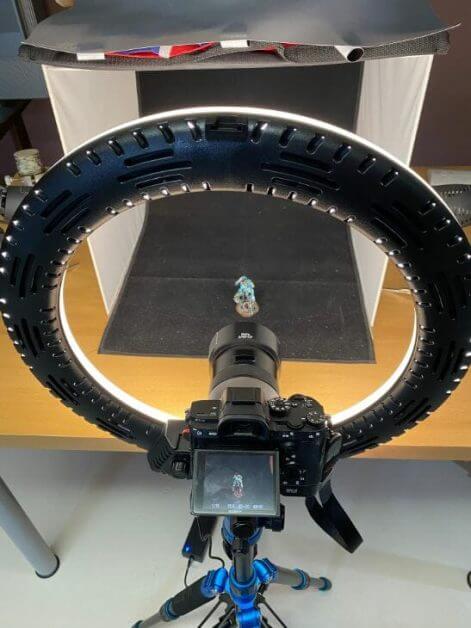 Camera positioned through an LED ring light for frontal miniature photography lighting
