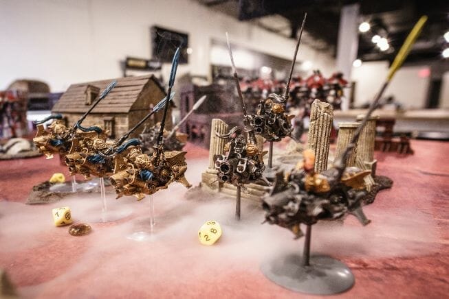 The History of Tabletop Wargaming - Miniature wargaming history through the ages, milestones and key points - Adeptus Custode models in a game of Warhammer 40k, with smoke effects 