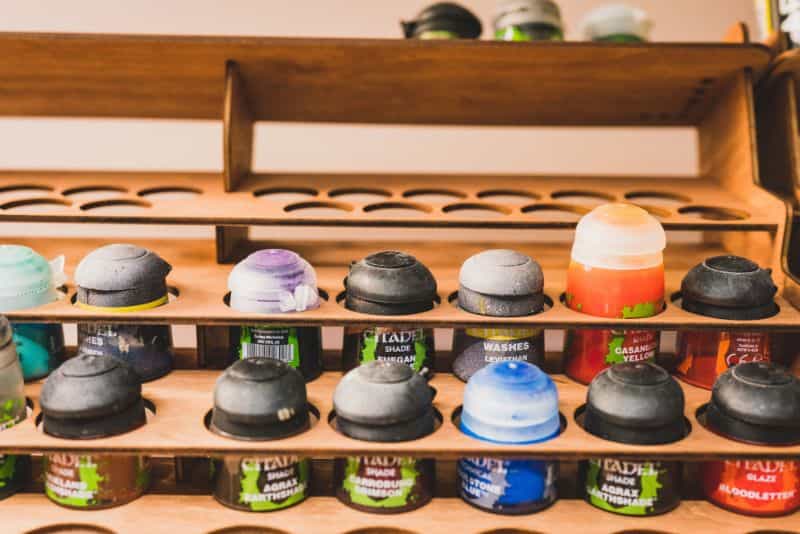 Understanding Acrylic Paint for Miniature Hobbies: Uses, Types, and Best Picks (Guide) - What is acrylic paint, it's uses, and best types - Citadel paint pots on a storage rack