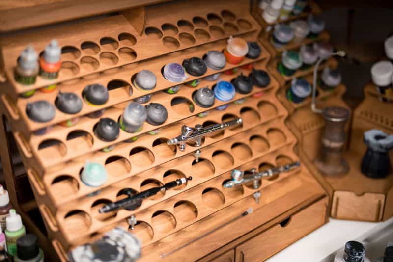 10 Money-Saving Hobby Tips for Miniature Painters - paint rack with paints and airbrush in it
