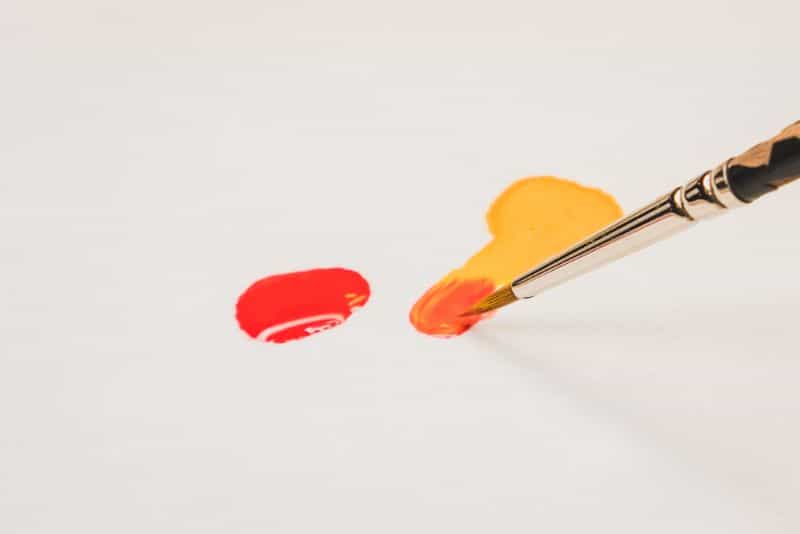 Understanding Acrylic Paint for Miniature Hobbies: Uses, Types, and Best Picks (Guide) - What is acrylic paint, its uses, and best types - mixing red and orange paint on a white colored palette
