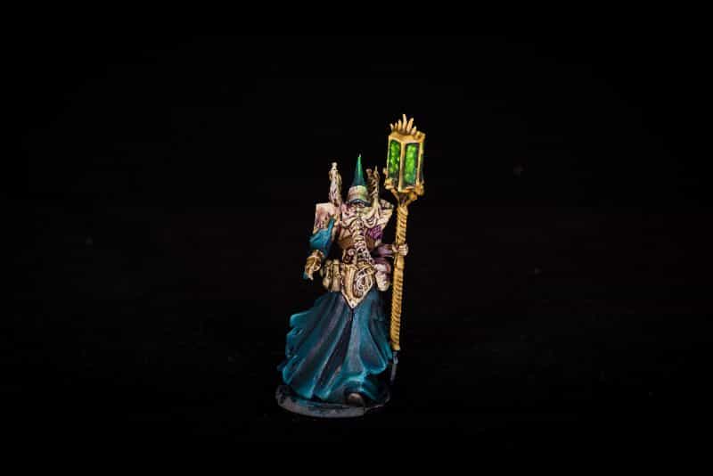 Miniature painted with blue, green, and other colors creating a vibrant figure photographed against a black backdrop