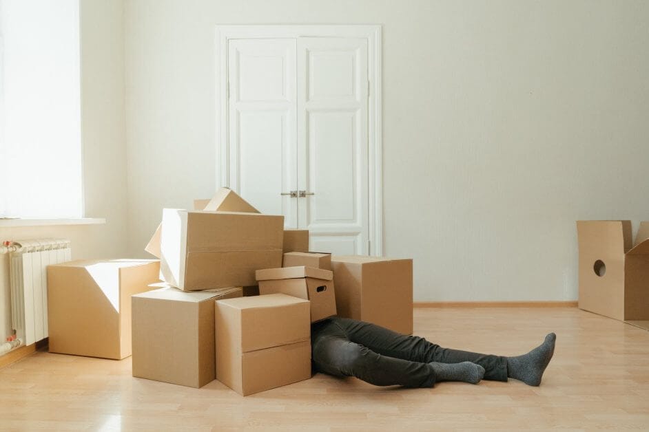 person in black leather boots lying on brown cardboard boxes