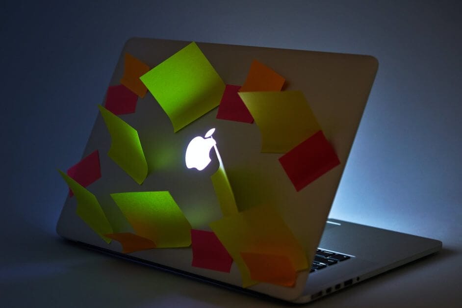 an apple laptop with sticky notes stuck on top panel