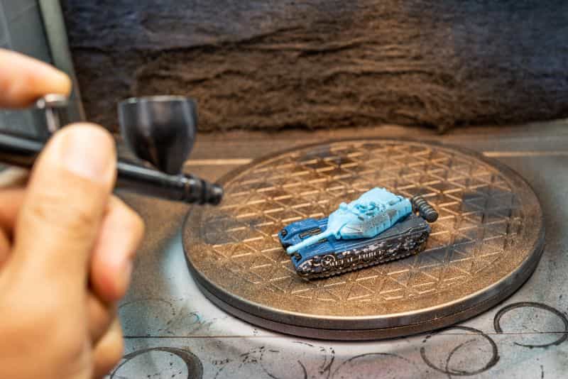 Badger Airbrushes: Best Beginner to Advanced Models for Painting Miniatures? - best badger airbrush for miniature painting - Airbrush spraying a toy tank with airbrush