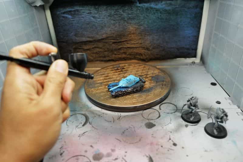 Applying vallejo surface primer on a miniature with an airbrush - toy and scale model miniatures shown in photo in a spray booth