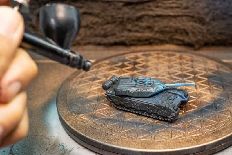 How to Paint Model Tanks (8 Basic Steps) - painting tanks - how to paint model tanks - close up spraying a tank with dark gray primer