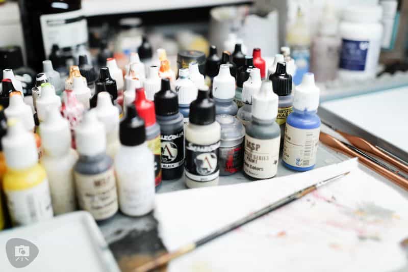Best Kind of Paint for Miniature Painting? - acrylic paint, oil paints, scale modeling, painting miniatures - Reaper paint bottles on hobby desk, mess