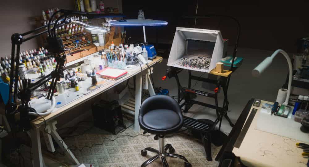 Well-lit hobby desk area with multiple lamps, showing a spacious setup for miniature painting