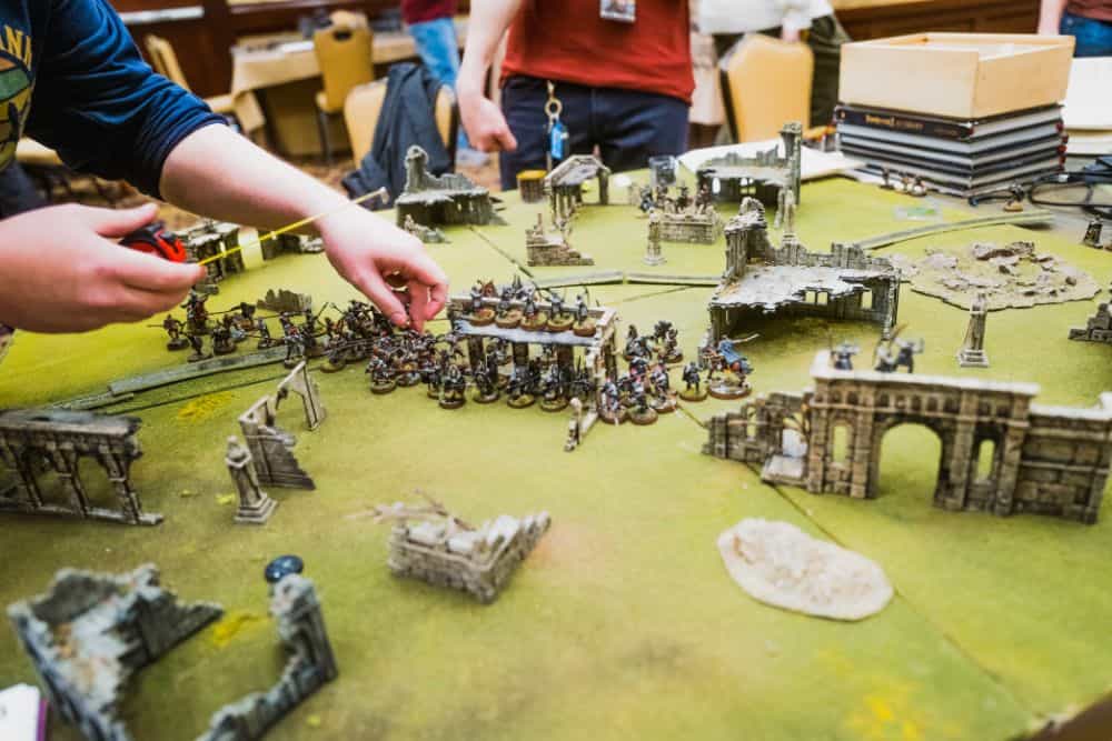 Can You Make a Living Painting Miniatures Full Time? - How to paint miniatures as a business - Painted miniatures with terrain on a tabletop wargame with players taking turns