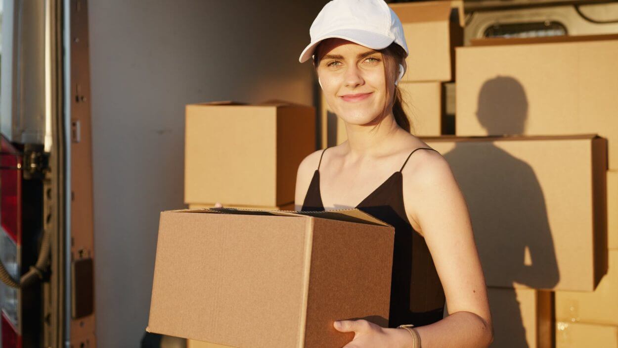 woman in black tank top holding brown cardboard box