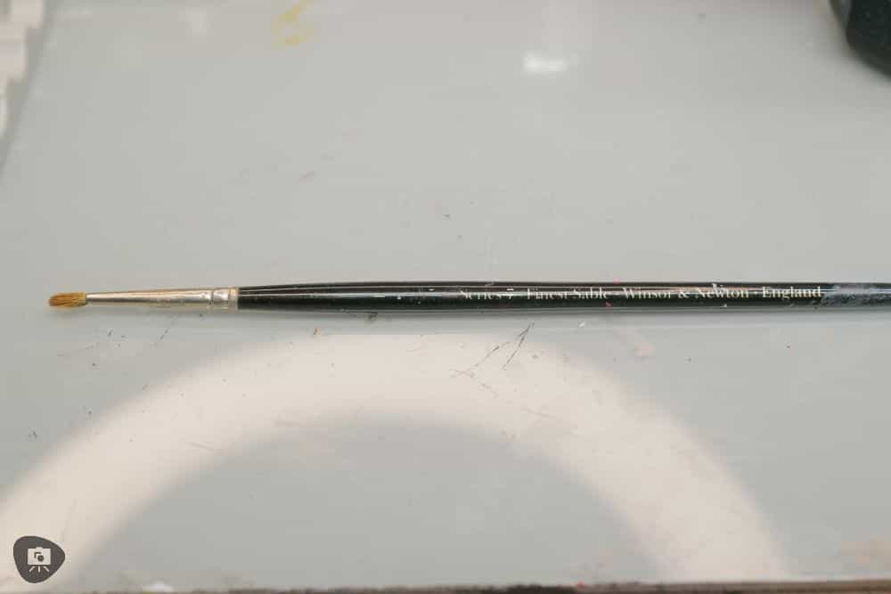 Miniature Paint Brush Care Tutorial - how to care for brushes for miniature painting - An old Winsor and Newton Series 7 paint brush on a gray colored tabletop