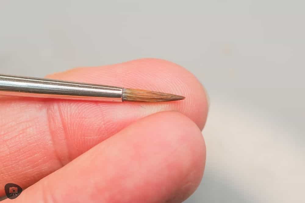 Miniature Paint Brush Care Tutorial - how to care for brushes for miniature painting - Shaping the pointed round brush tip back into a fine point with my fingers close up image