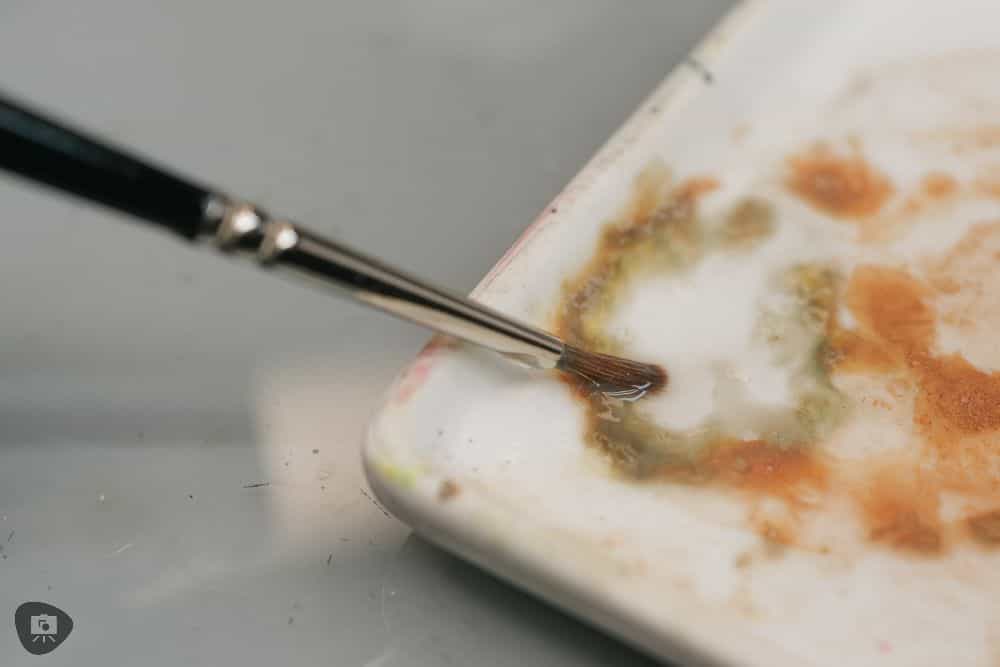 Miniature Paint Brush Care Tutorial - how to care for brushes for miniature painting - rinsing off paint brush in a small glazed white dish