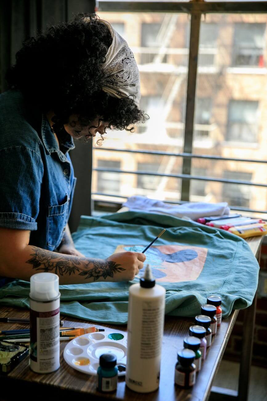 curly haired artist painting on cloth