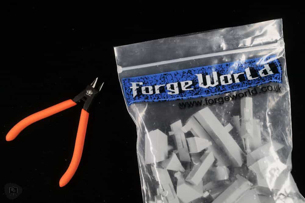 Redgrass Games Sprue Cutter and Precision Nipper Review - RGG sprue cutter RGG precision nipper - Forgeworld modeling resin in a plastic bag with the RGG sprue cutter on a black tabletop