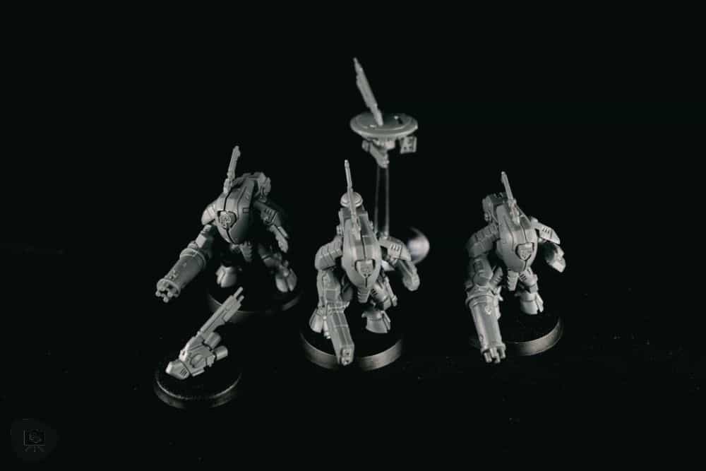 How to Paint Plastic Miniatures (Step-by-Step) - Fully assembled Tau models photographed with a black background, unpainted plastic