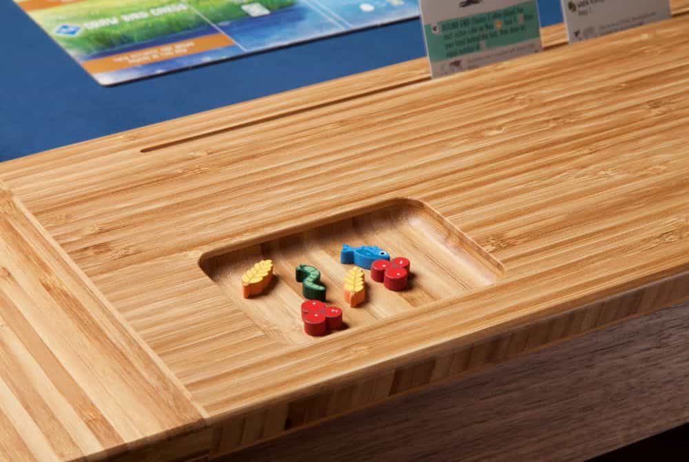 A built in token tray holds colorful pieces for a board game