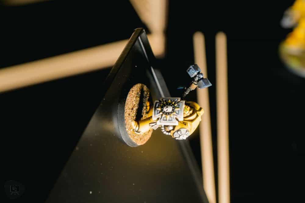 Yellow armored Space Marine miniature held securely on its base to a black magnetic tray surface