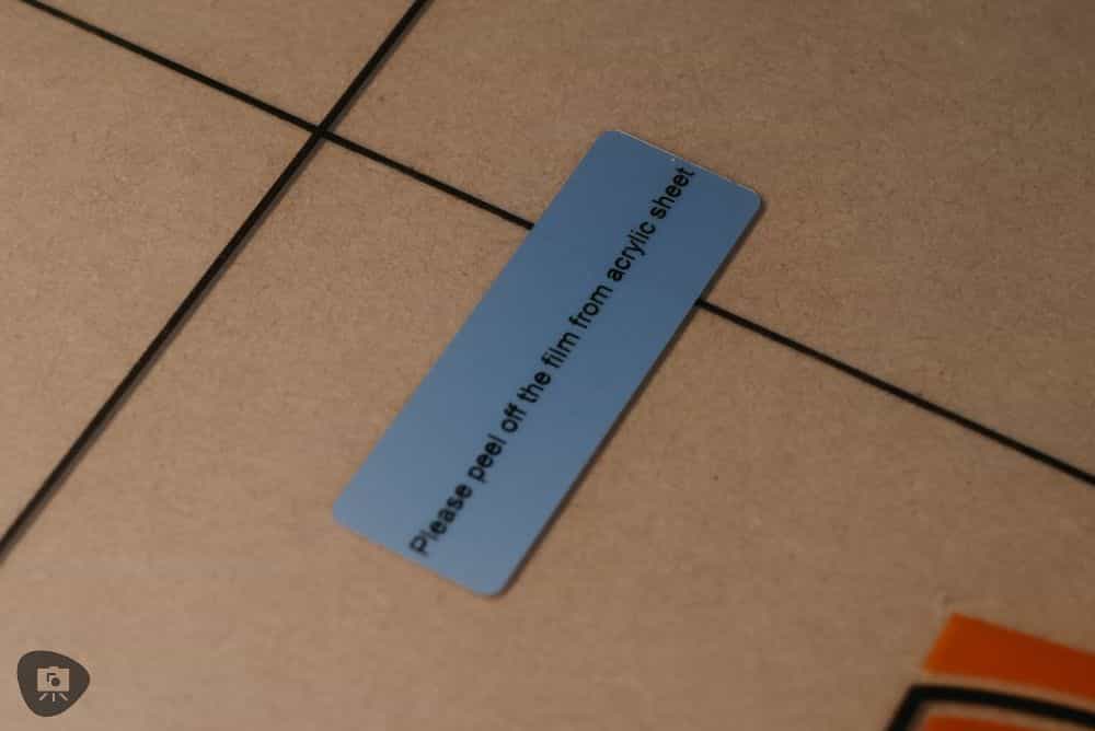 Best Budget Magnetic Miniature Carrying Case - close macro photo of the instructional sticker on the plastic sheeting on the acrylic wall