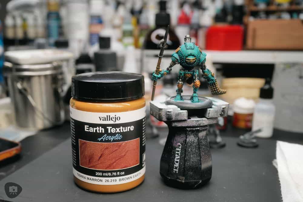 Zenithal Dry Brushing to "SlapChop" Paint Miniatures - side by side vallejo texture mud pot and the model on a citadel painting handle