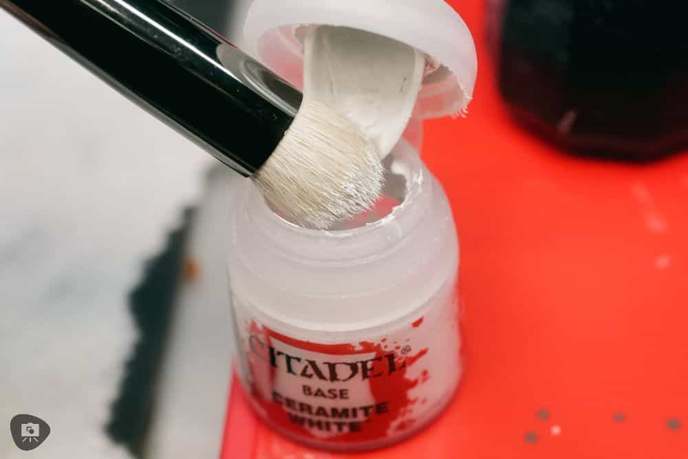 Zenithal Dry Brushing to "SlapChop" Paint Miniatures - loading a dry brush in white paint, dipping in a pot of citadel base ceramite white