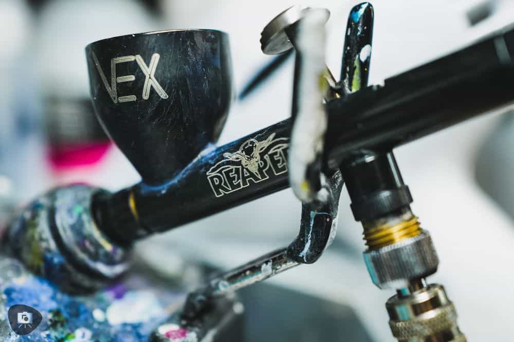 Reaper Vex airbrush review - Reaper airbrush in the airbrush holder close up of paint cup and logo