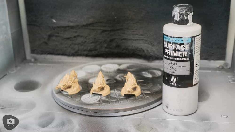 Speed Painting Board Game Miniatures: A Step-by-Step Guide - vallejo surface primer bottle and miniatures in a spray booth