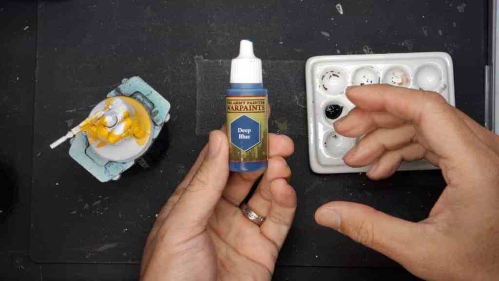 How to paint black on miniatures - tips steps - Army Painter deep blue bottle paint in hand top down