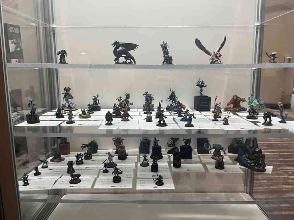 Display case at GenCon showcasing various painted miniatures from the painting competition