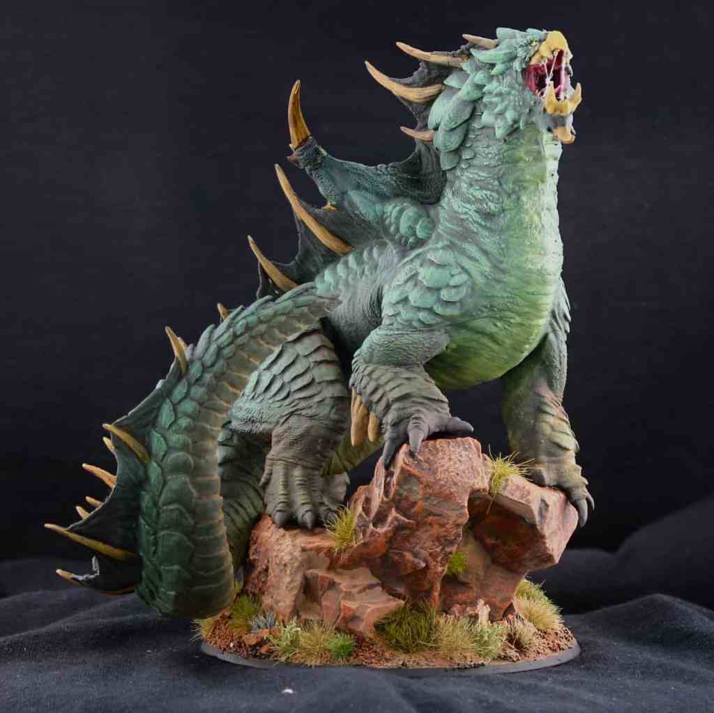 Front view of a painted dragon miniature displayed at GenCon, inspired by a crocodile color scheme