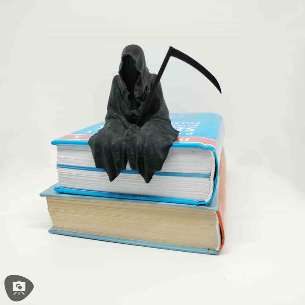 Grim reaper figurine holding a scythe, seated on a stack of books