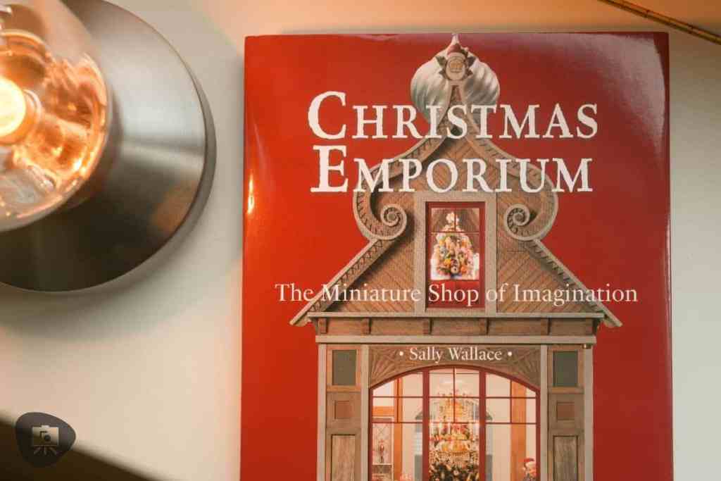 Top-down view of the 'Christmas Emporium' book with a warm-lit lamp and decorative festive design