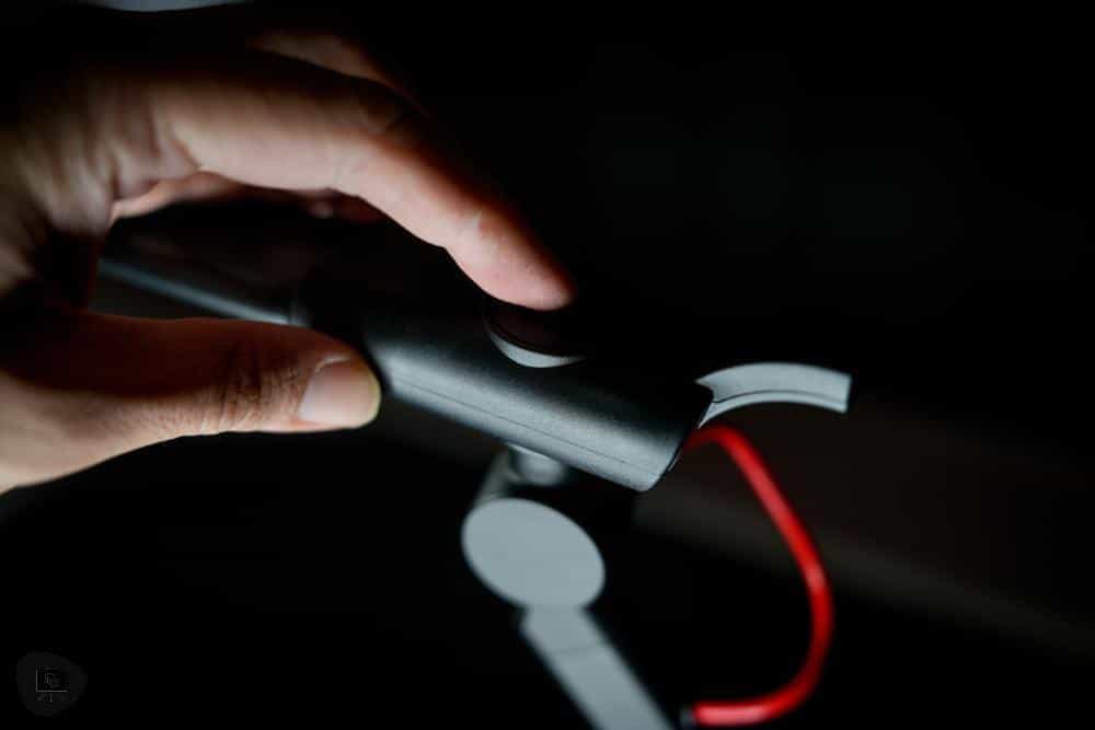 Close-up of a hand pressing the power button on the Redgrass SOLO desk lamp