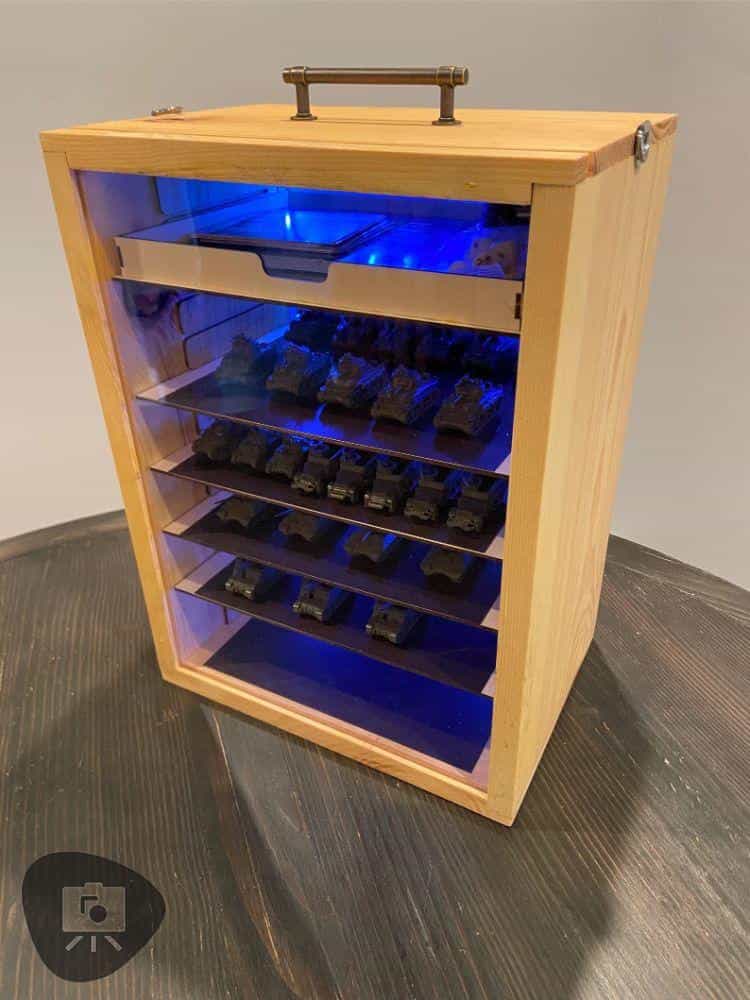 Wooden miniature carrying case with blue LED lighting and magnetized trays holding tanks and models