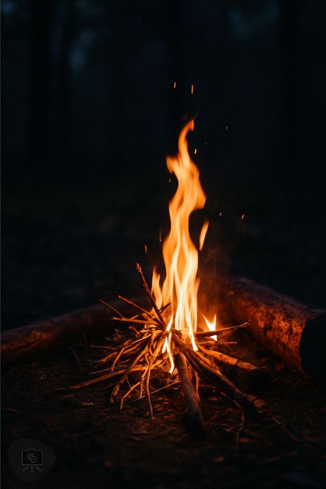 Small campfire with yellow-white center and orange flames rising into the air, used as a real-world fire reference.