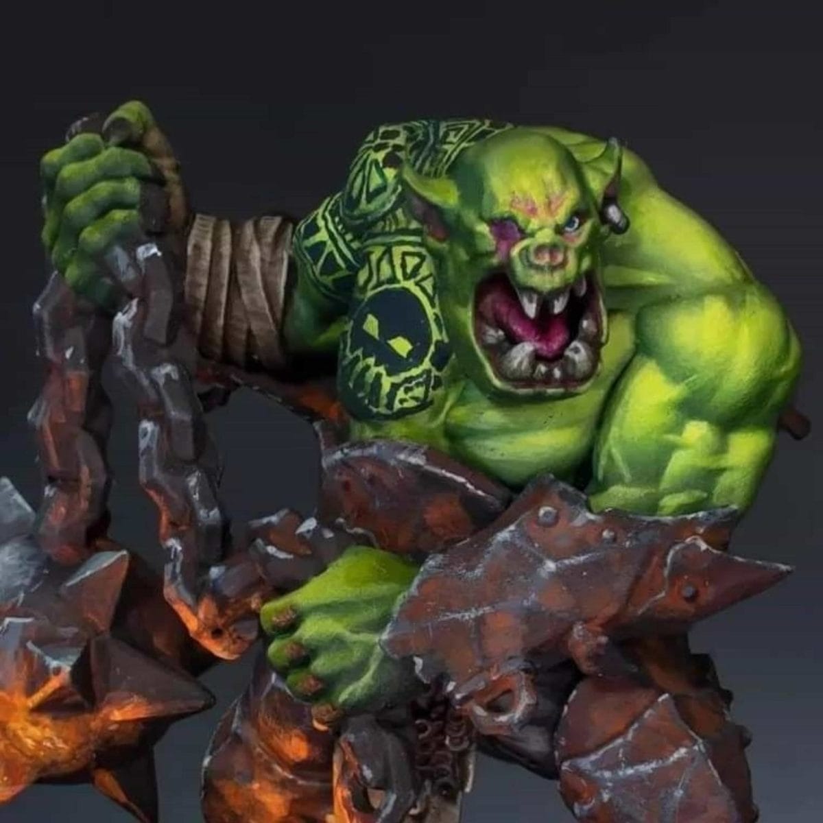 Close-up of a muscular green-skinned Ork wielding a massive spiked chain weapon, showing detailed tattoos, weathered armor, and expressive miniature painting work.