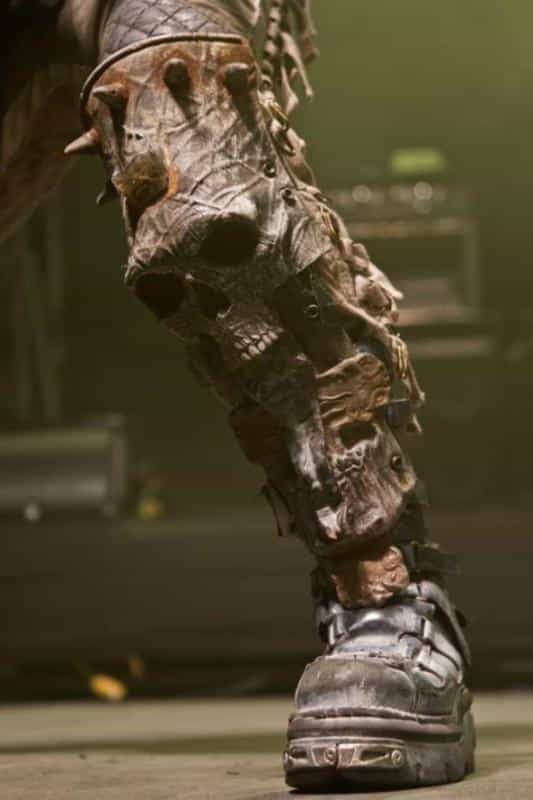 Close-up of an Ork leg wearing heavy, skull-adorned armor and a metal boot, showing gritty textures and weathered materials for miniature painting reference.