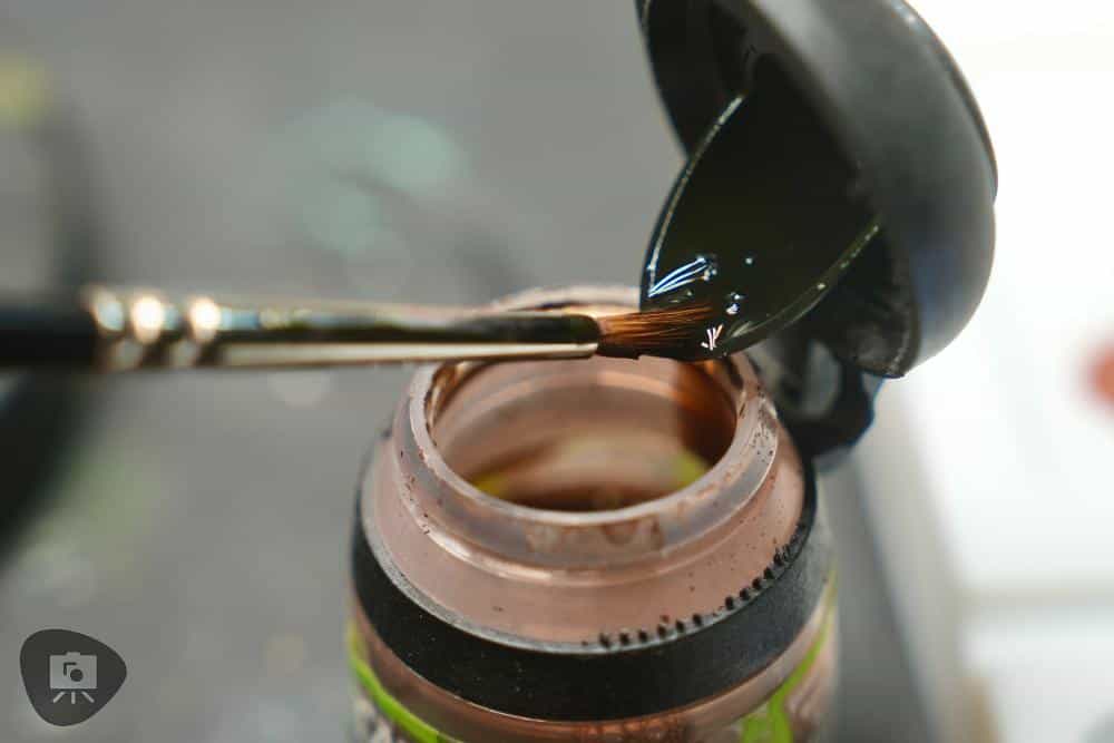 Loading a brush with a controlled amount of shade wash for miniature painting.